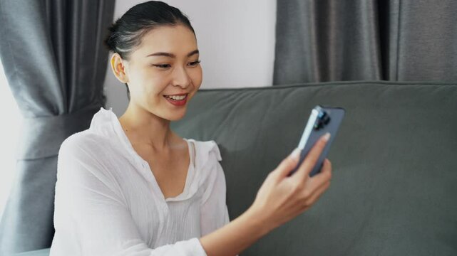 Beautiful Asian girl happy video chatting or having a facetime conversation on smartphone. Lifestyle and technology concept