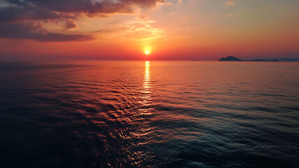 Fototapeta premium Beautiful sunset on Andaman sea at Windmill View Point near Laem Promthep Cape, A stunning sunset paints the sky in vibrant hues of orange and red over a serene ocean.