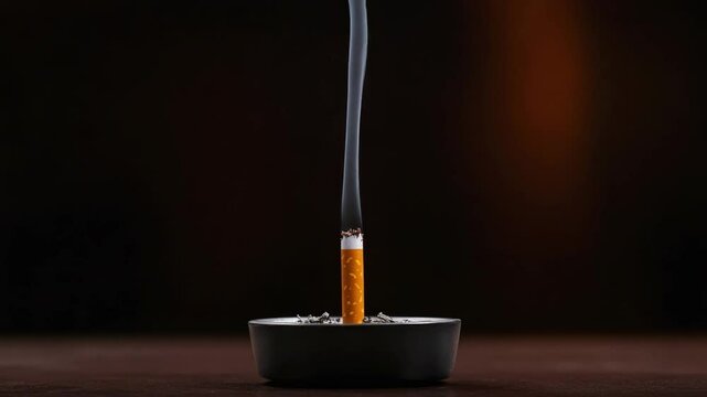 Smoky cigarette resting in an ashtray with wisps of gray smoke drifting upwards in a dimly lit environment