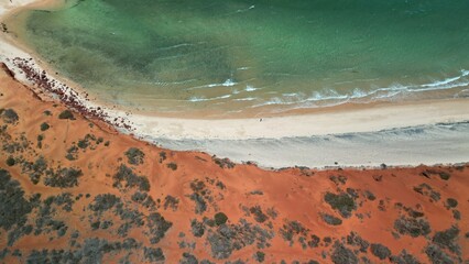 drone image of red sand dunes meeting the ocean