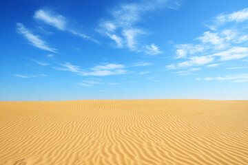 Desert landscape featuring sun-bleached sand dunes under a clear blue sky with gentle clouds