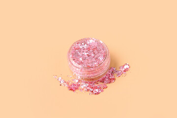 Jar of pink glitter on beige background