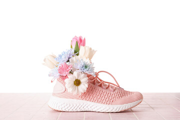 Sneaker with spring flowers on table against white background