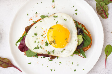 Delicious sandwich with fried egg and greens on light background