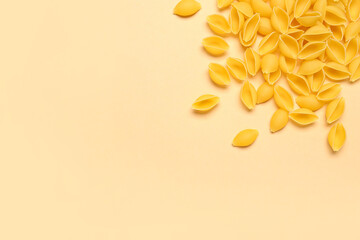 Heap of raw conchiglie pasta on yellow background