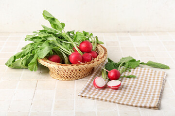 Wicker basket of ripe radish with green leaves on table