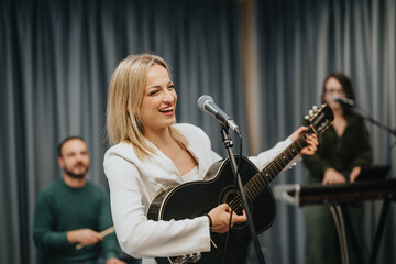 Obraz premium A lively band performing in a music studio. The lead singer plays the guitar while other members contribute with instruments, creating an energetic and collaborative ambiance.