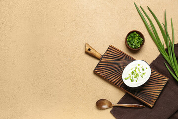 Bowls of tasty sour cream with green onion on beige background