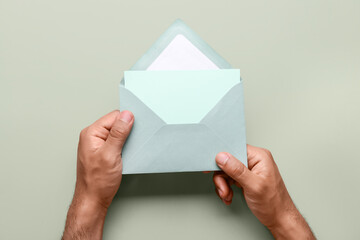 Male hands with envelope and blank card on color background, closeup