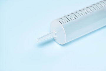 Part of large medical syringe without needle on blue background.