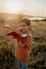Smiling preschool child boy plays with craft wooden retro styled airplane
