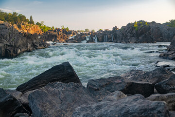 turbulent Mountain River with waterfalls and rapids at sunset.
