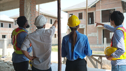 Group of architects and engineers work together to assess the residential home construction site's progress