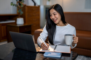 A woman is sitting at a table with a laptop and a notebook