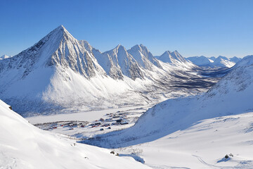 Fototapeta premium Stunning view of snow-covered mountains in the Arctic during bright winter day with clear blue sky