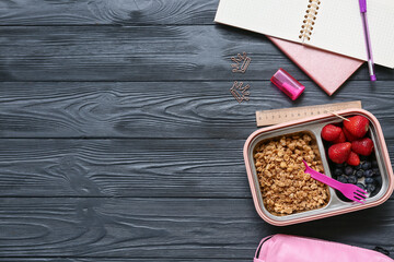Lunch box with tasty food and school stationery on dark wooden background