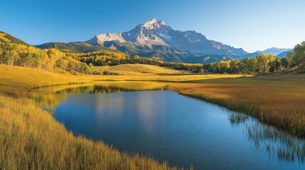 A clear blue sky overlooks a mountain landscape featuring a small pond surrounded by dense forest