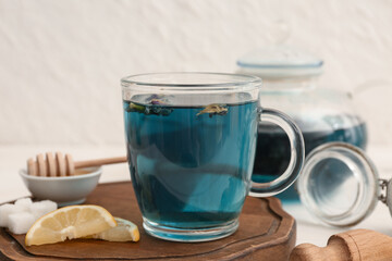 Cup of butterfly pea flower tea on wooden tray, closeup