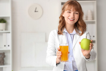Female nutritionist with glass of juice and apple in office