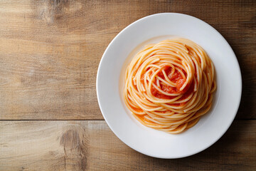 A plate of pasta topped with rich tomato sauce and fresh basil, served on a wooden table, showcasing a delightful and flavorful Italian meal.