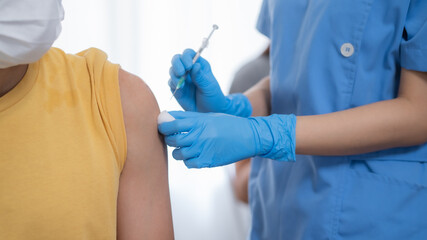 Hand of young woman nurse, doctor giving syringe vaccine, inject shot to Asian arm's patient. Vaccination, immunization or disease prevention against flu or virus pandemic concept