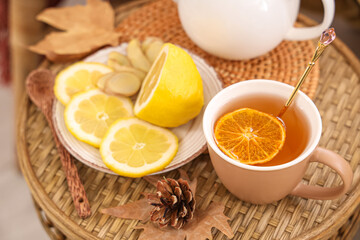 Teapot, cup of green tea and plate with ginger and lemon on coffee table in room. Closeup