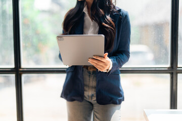 Businesswoman using digital tablet near window in office