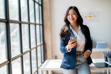 Portrait of a smiling businesswoman using mobile phone in modern office