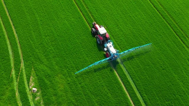 Pesticide  aplication. A tractor with chemical sprayer working on a field.