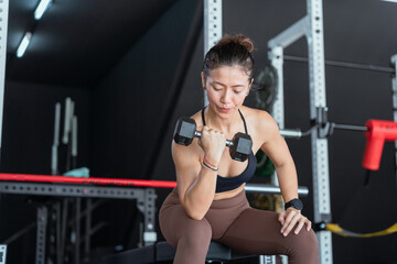 Fitness enthusiast lifts dumbbell in gym during workout session focused on strength training and...
