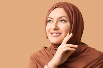 Smiling Muslim woman in hijab on brown background