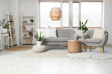 Cozy sofa, armchair, basket and shelving units in interior of living room