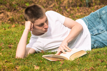 Teenage boy reading a book in a park