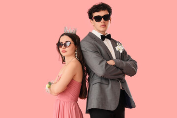 Pretty prom couple in sunglasses on pink background