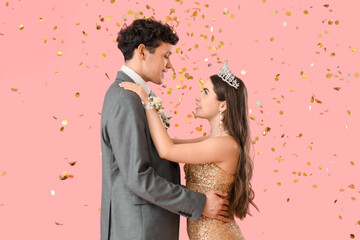 Pretty prom couple with confetti dancing on pink background © Pixel-Shot