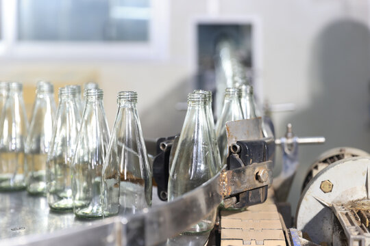 Glass bottles of purified drinking water inside drinking water or beverage factory which has automated conveyor production line. Water manufacture business. Beverages industry business.