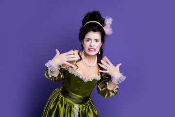 Young woman in vintage green dress with a humorous pose against a vibrant purple background showcasing baroque elegance and whimsical charm