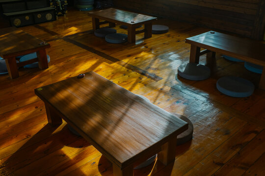 Sunlight Wooden Tables and Stools,the wooden tables and stools and the prominent feature of sunlight casting shadows on them.