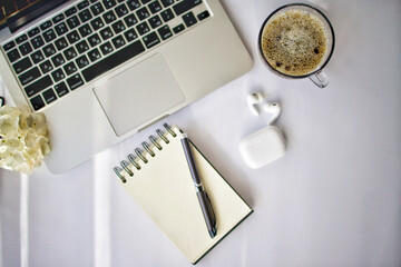A laptop, a cup of coffee, and a notebook on the table