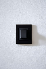 Interrupteur noir sur un mur de cr&eacute;pis blanc