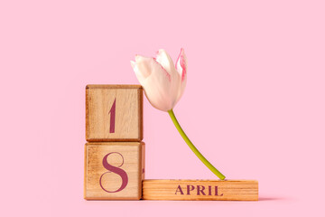 Cube calendar with date 18 April and beautiful tulip flower on pink background
