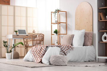 Interior of teenager's room with bed, workplace and plants