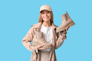 Stylish young woman with boots on blue background