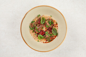 Portion of gourmet pasta orzo with meat and basil