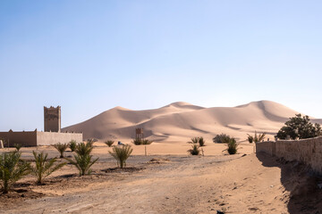 View of sand dunes in Merzouga, Traditional house in mud bricks, Morocco.  Erg Chebbi Sahara desert, North Africa
