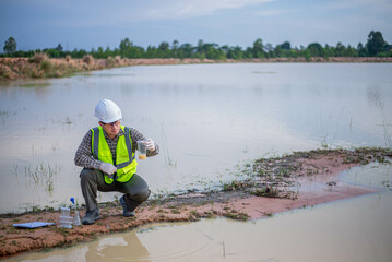 A biologist is collecting water samples from a pond for research in a science lab.