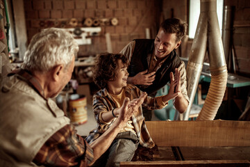 Happy grandfather teaching grandson carpentry with father in workshop
