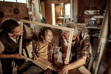 Happy grandfather teaching grandson carpentry with father in workshop