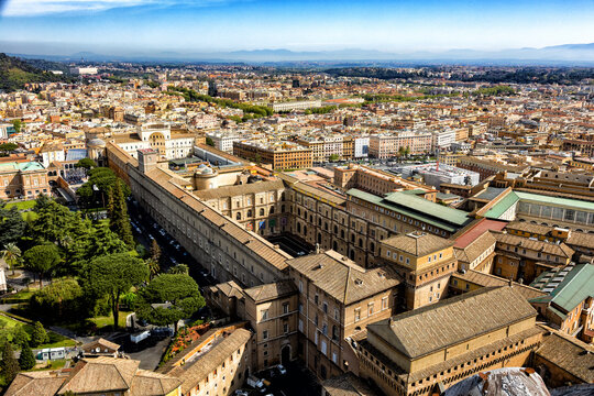 The vast Vatican Museums complex and monumental courtyards overlook the dense Rome cityscape under a blue sky. A majestic architectural panorama inspiring European cultural travel campaigns.