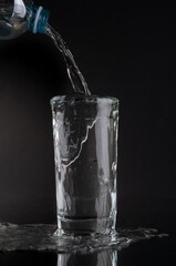 Pouring soda water into glass on a black background